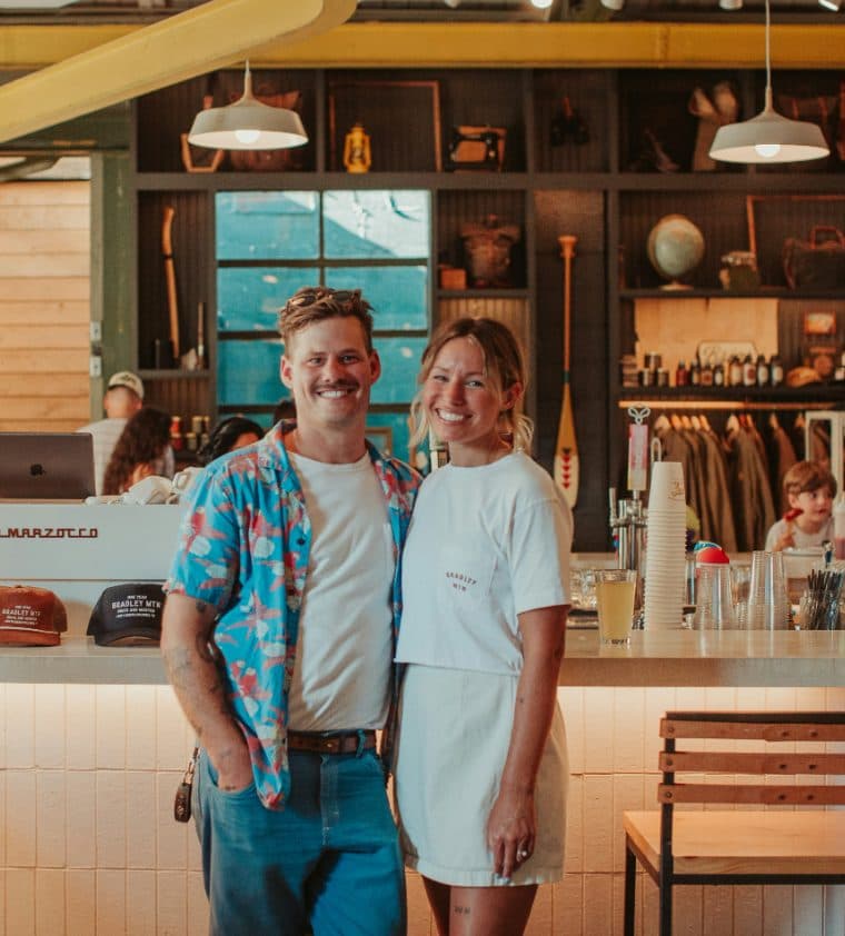 Two cafe owners standing together behind the counter of their shop
