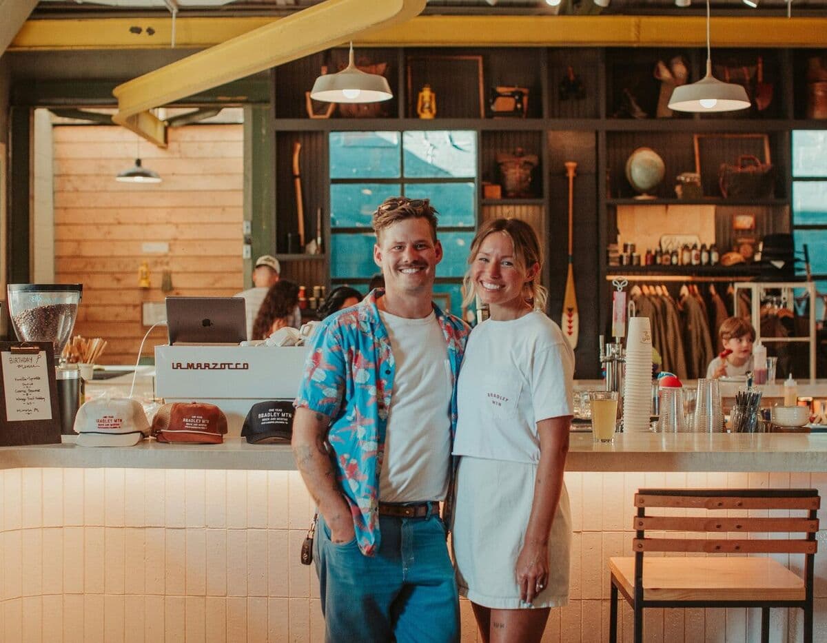 Two cafe owners smiling in front of their shop