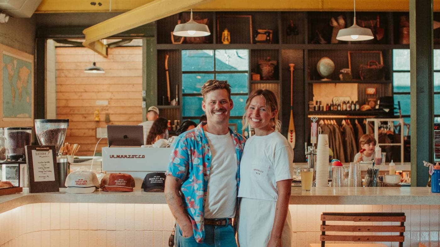 Two cafe owners smiling in front of their shop